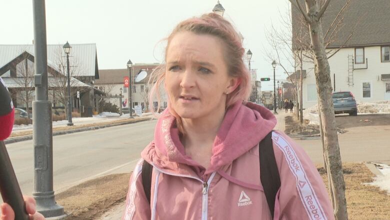 Young woman with blonde hair in a pony tail wearing pink hoodie and jacket.