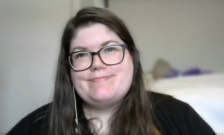 A white woman wearing glasses in a black sweater faces the camera.