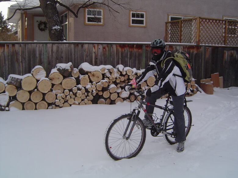 A woman sits on her bike, surrounded by snow.