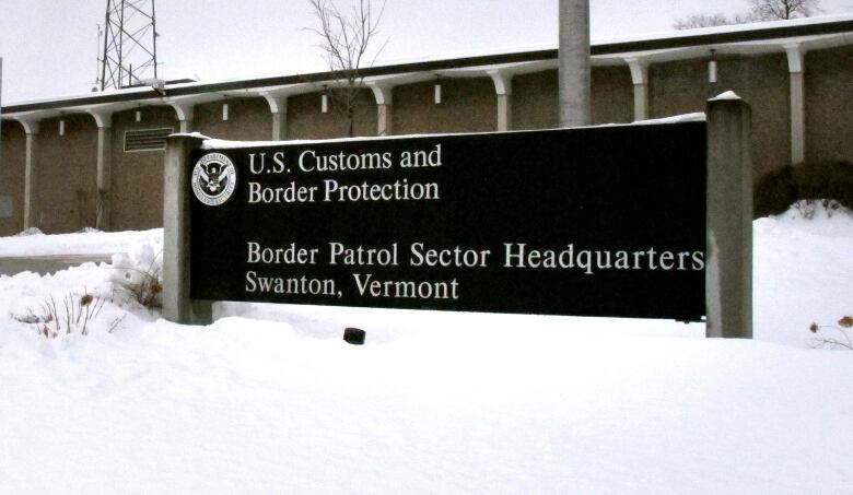  A snow-covered sign is seen in front of a one-storey office building. 