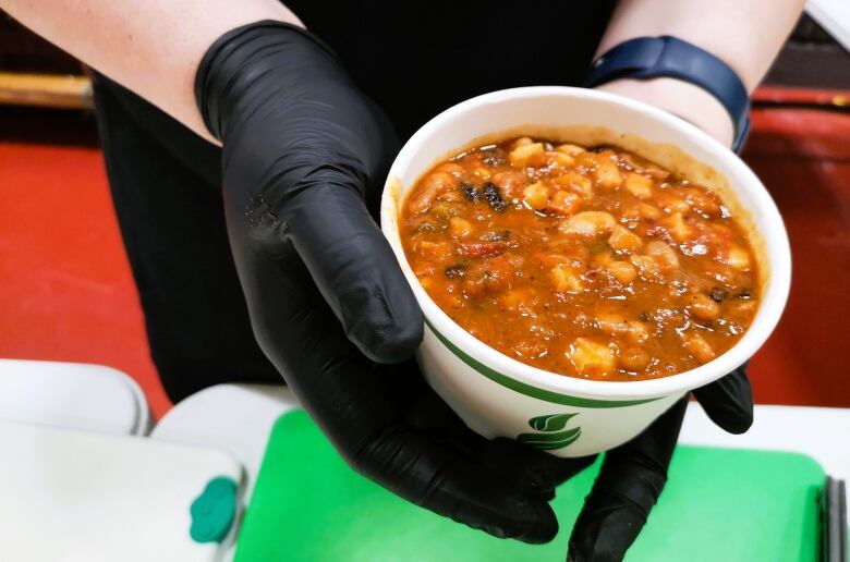 A bowl of chili is offered to a guest.