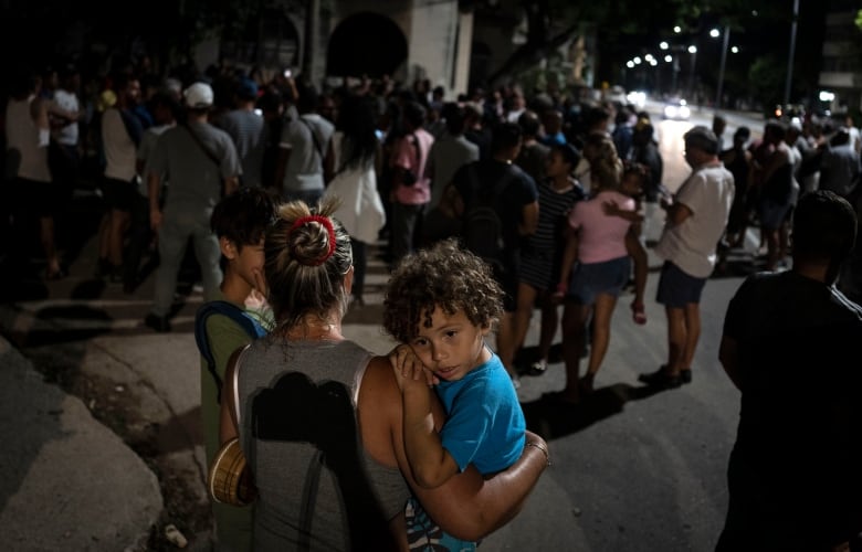 A child rests in his mother's arms during a protest calling for the restoration of electrical service after six days of blackouts due to the devastation of Hurricane Ian in Havana, Cuba, Saturday, Oct 1, 2022.