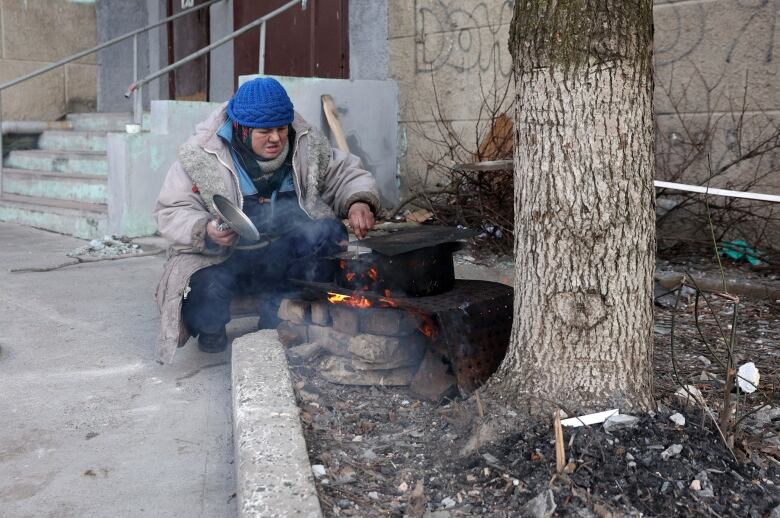 A woman cooks food outdoors in Bakhmut, Ukraine.