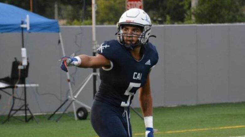 A player in football gear lines up to run a route outside.