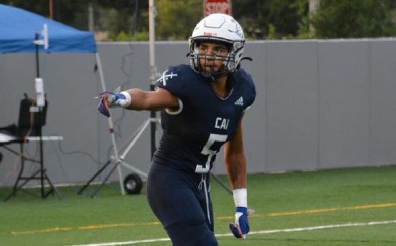 A player in football gear lines up to run a route outside.