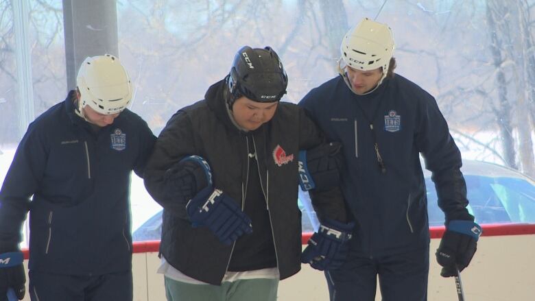 Three people link arms on ice.