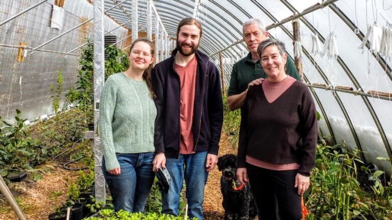 Family poses for camera in a greenhouse.