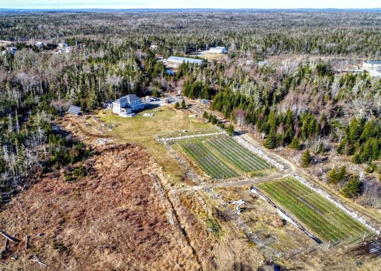 A drone shot of a farm building and cultivated land behind it.