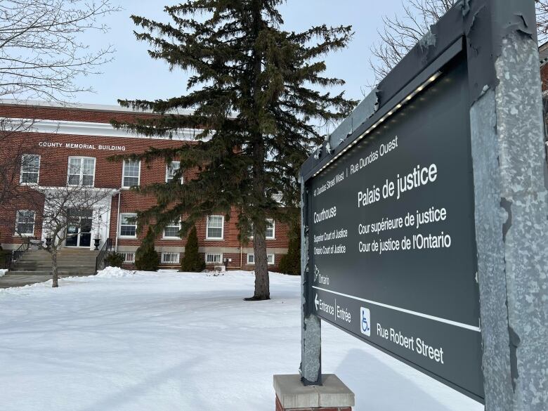 A red brick building with the words County Memorial Building can be seen in the background of a sign declaring it a courthouse. There are large trees on a snowy lawn.