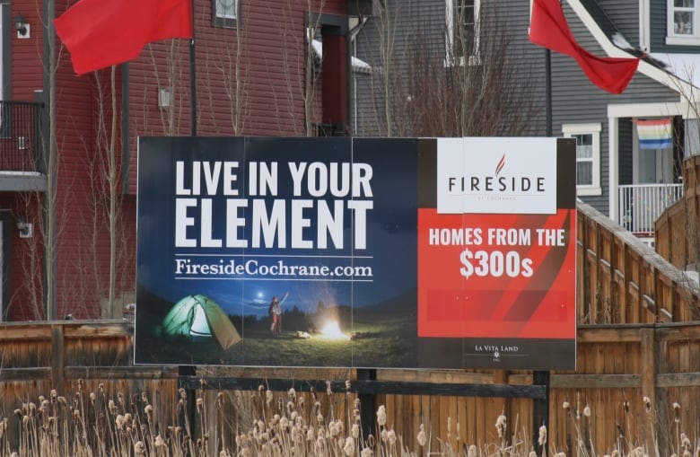 A photo shows a developer sign beside a new housing development in Cochrane, Alberta.