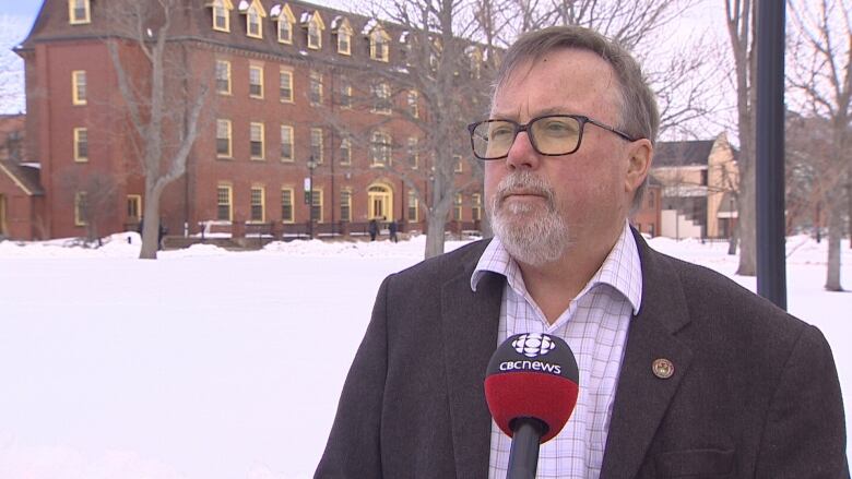 UPEI political scientist Don Desserud stands facing the camera on the school's campus.