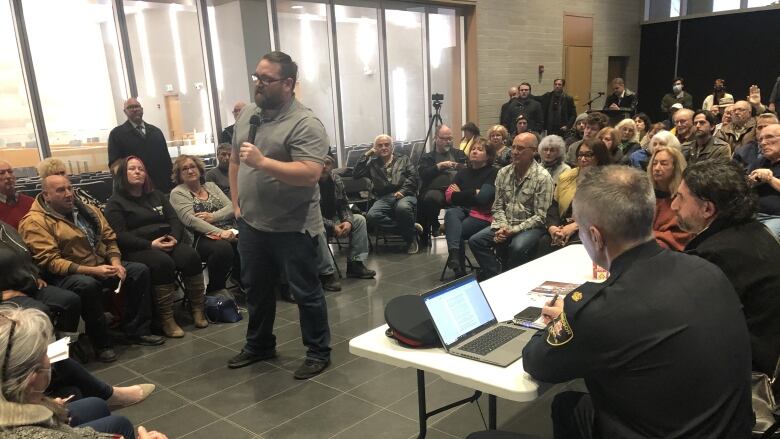 Nick Amlin address a crowd, which is seated on three sides of him.