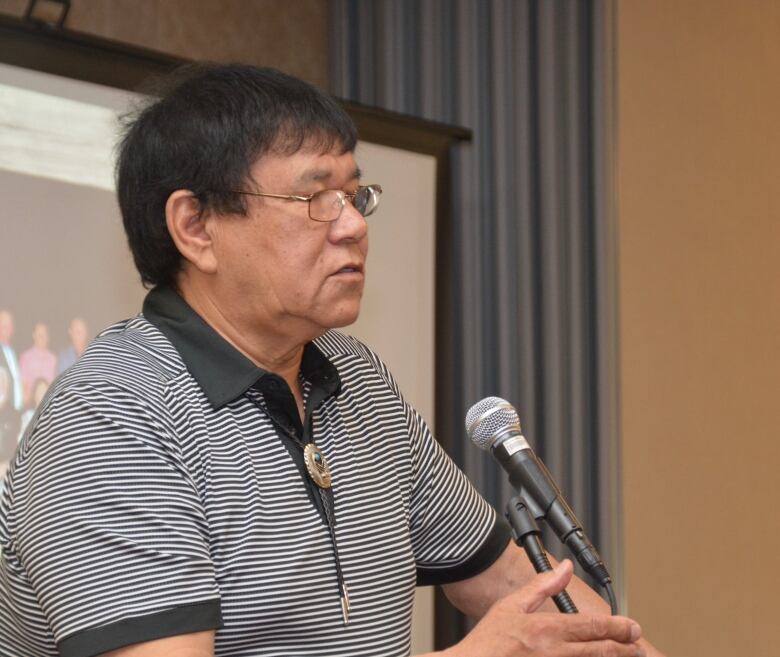 An Indigenous man stands at a podium. 