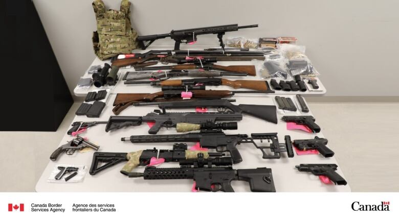 A table full of guns and weapons is shown. 