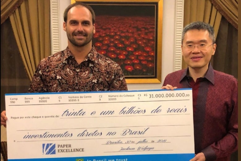 Two men smile and pose for a portrait while holding an oversized novelty cheque.