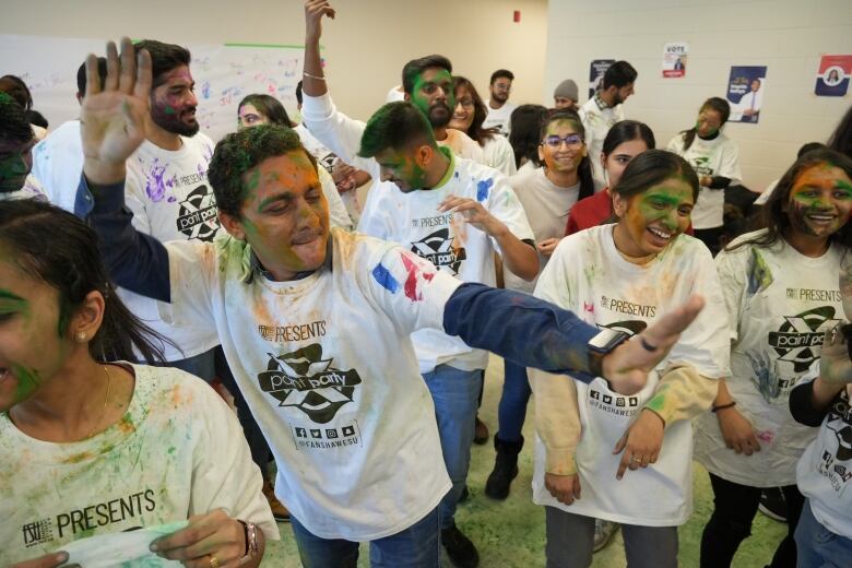 students dancing in white shirts covered in colourful powder