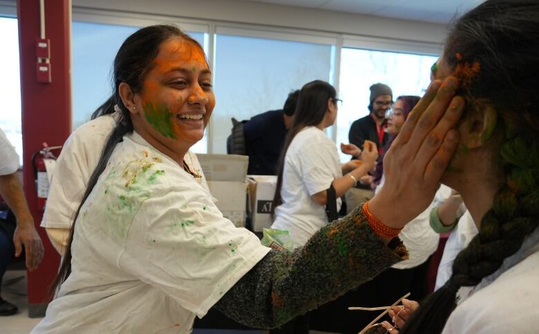 a woman puts colour on anothers face with her hand