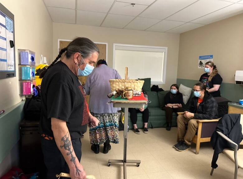 A group of people sit and stand together in a hospital room.