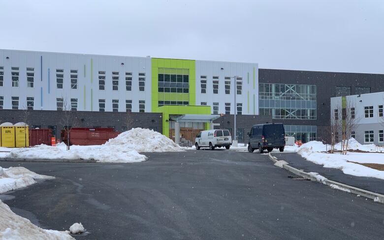 Vans are parked outside a new high school that's under construction