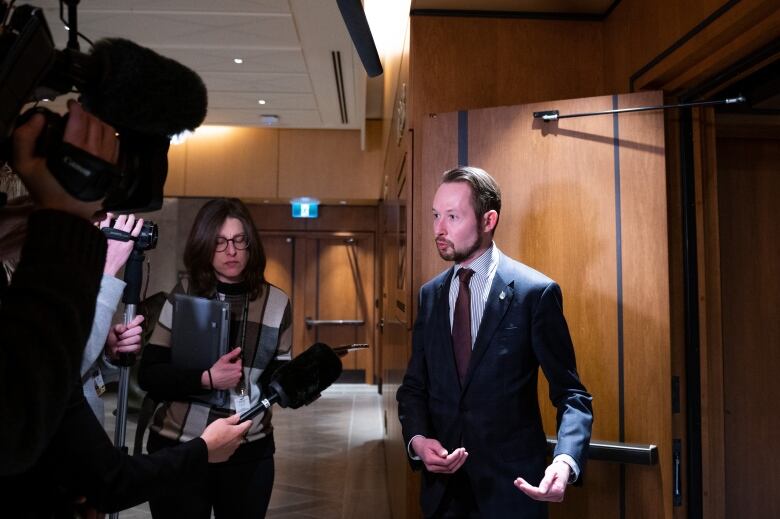 A member of Parliament speaks to journalists on camera.