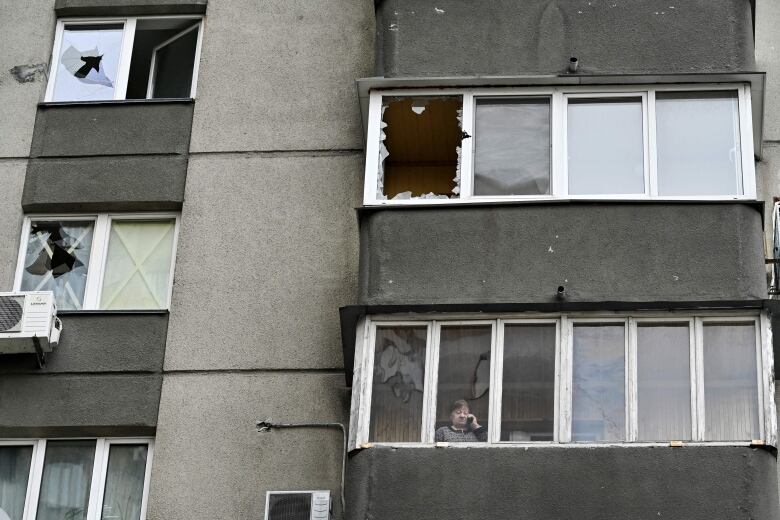 A Kyiv resident looks out of a building with damaged windows on Thursday.