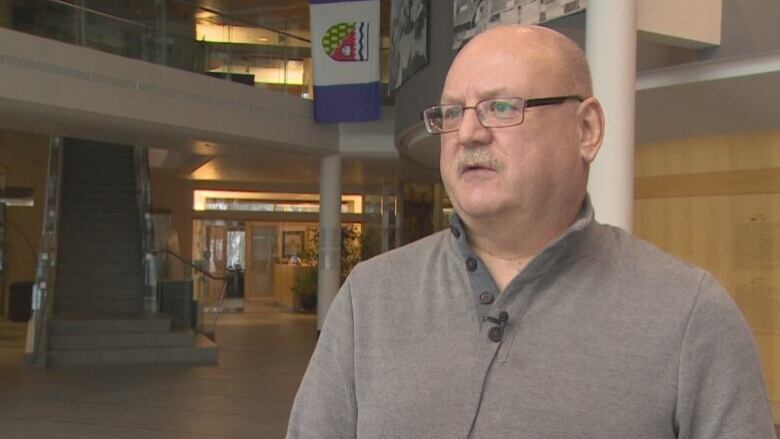 A close up of a man standing in the lobby of an institutional building.