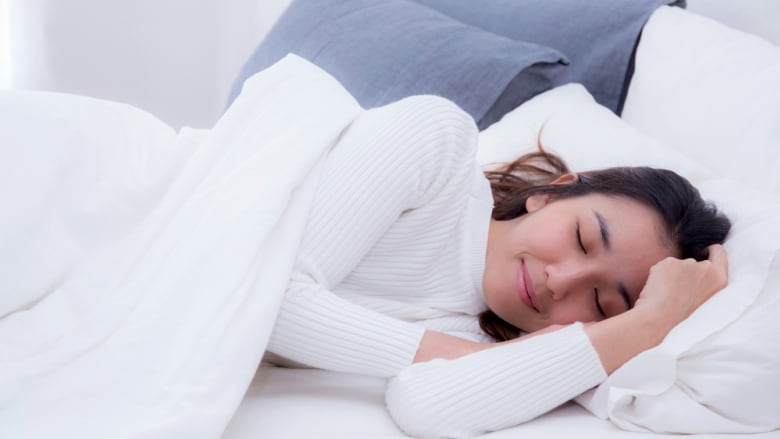 Woman sleeping on her side in a bed. 