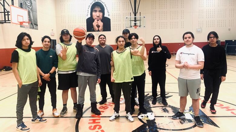 Basketball players stand in a row posing for a picture holding a basketball. 