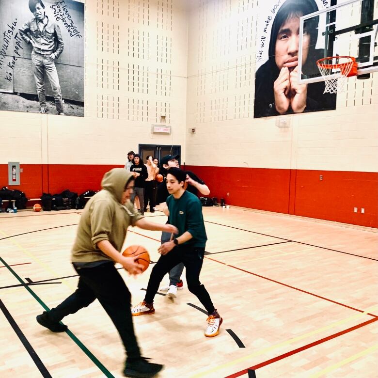 Basketball players dribbles a ball on a court against an opposing person. 