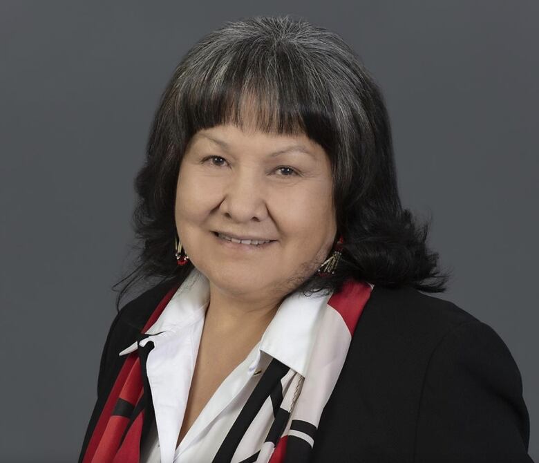 Georgina Martin smiles at the camera in a portrait photo with a grey background. 