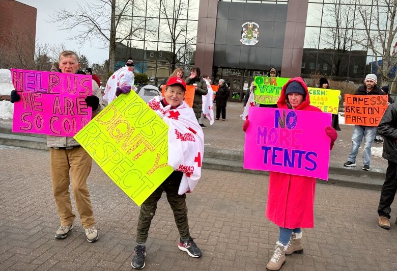 Protesters carrying signs set up in front of CBRM city hall.