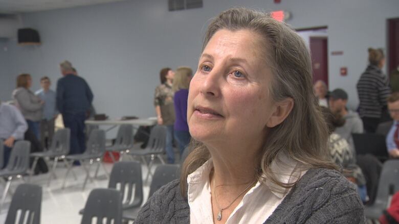 A lady speaks in a room of people prior to a meeting.