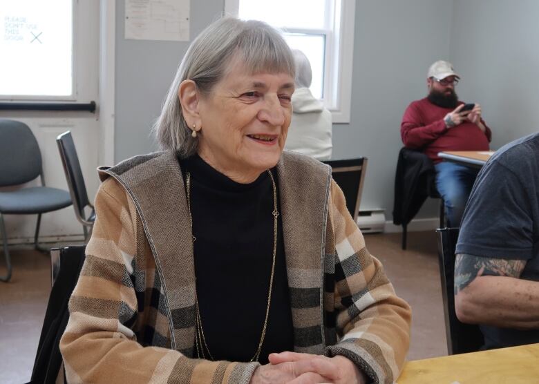 A fashionable older woman in a checked coat and a black top.