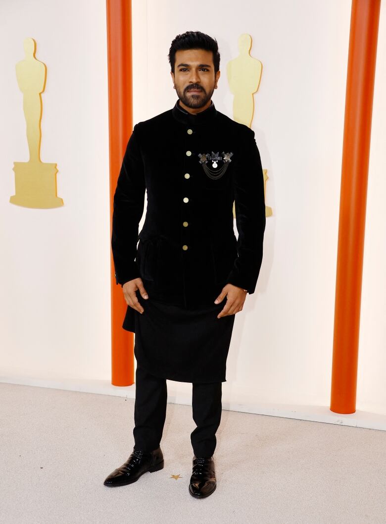 A man wearing a dark suit poses on a champagne-coloured carpet.