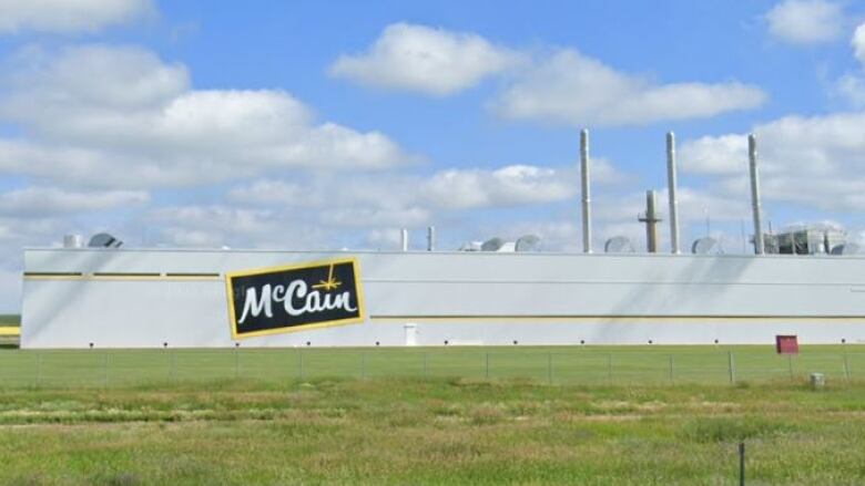 A very large food processing facility is seen from an adjacent rural highway