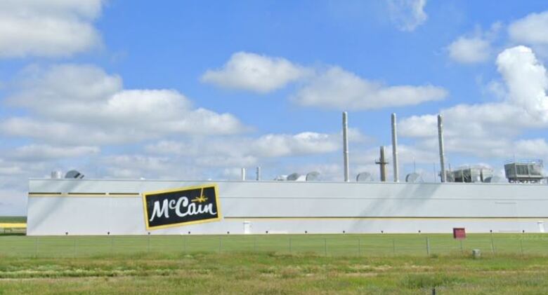 A very large food processing facility is seen from an adjacent rural highway