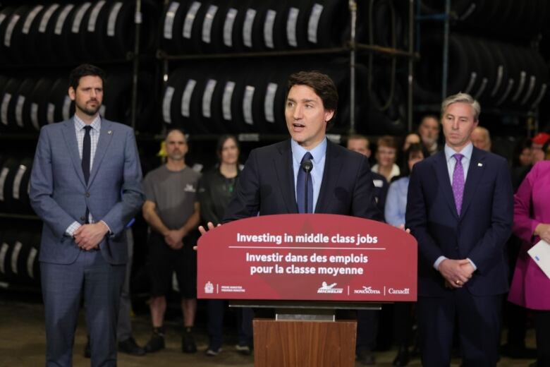 The prime minister speaks at a podium as others look on.