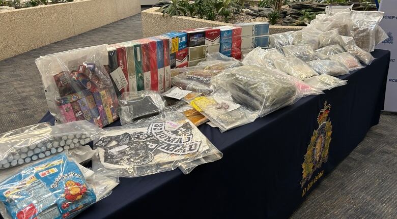 A table is crowded with cartons of cigarettes, bags of drugs and gang paraphernalia.