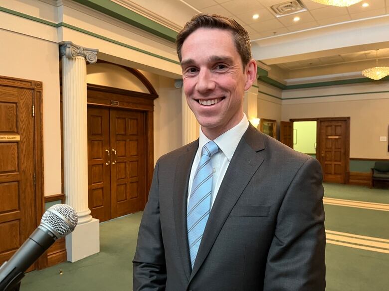 A man wearing a suit looks at the camera and smiles.