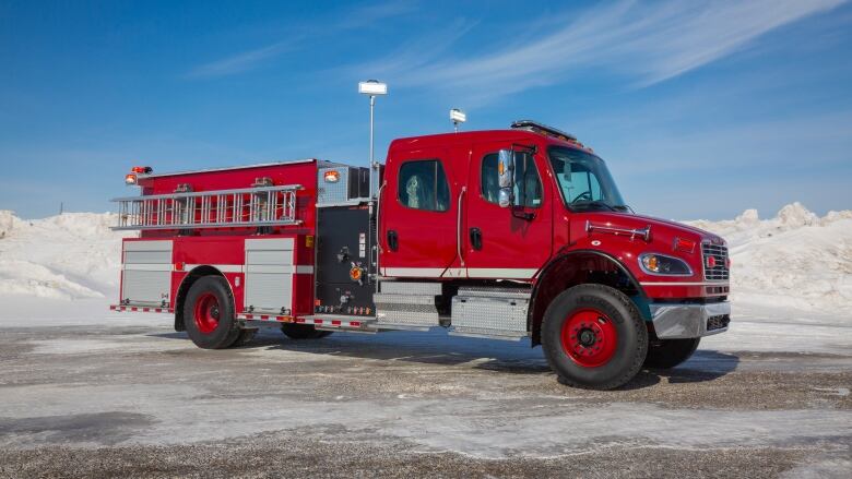 A red fire truck in front of a snowbank. 