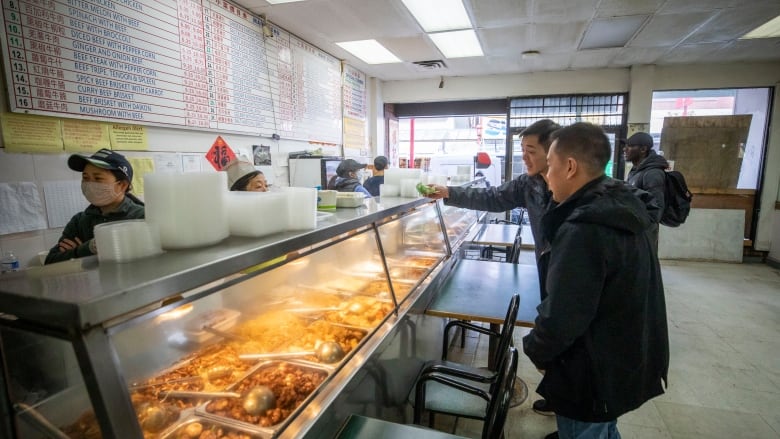 Two customers stand at a counter ordering food