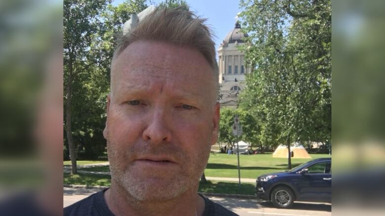 Selfie of man standing in front of Manitoba legislature.