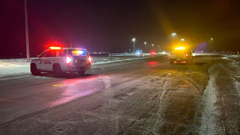 RCMP vehicles with their lights on are seen on a slippery-looking winter road.