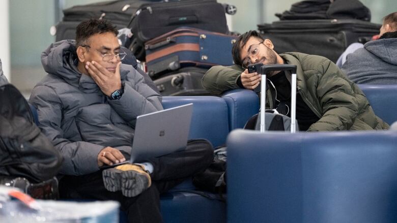 Two passengers waiting with their luggage at their airport. 