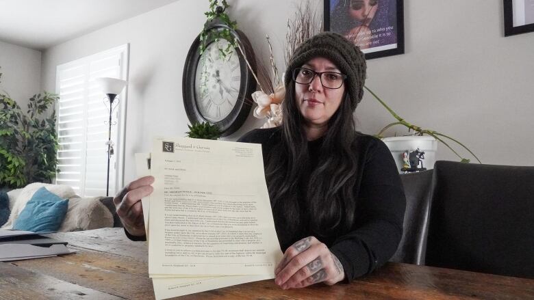 A woman holds up a letter at a table.