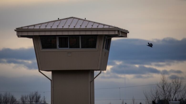 A prison tower is seen against a stormy sky.