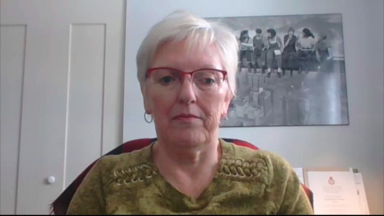 a woman with short white hair and red glasses