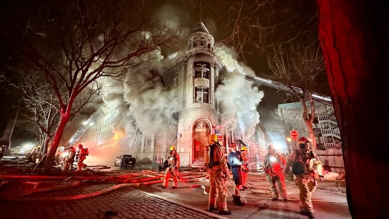 a building engulfed in flames and smoke with firefighters