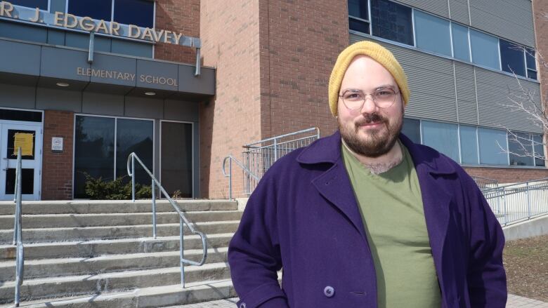 A man in front of a school voting poll. 