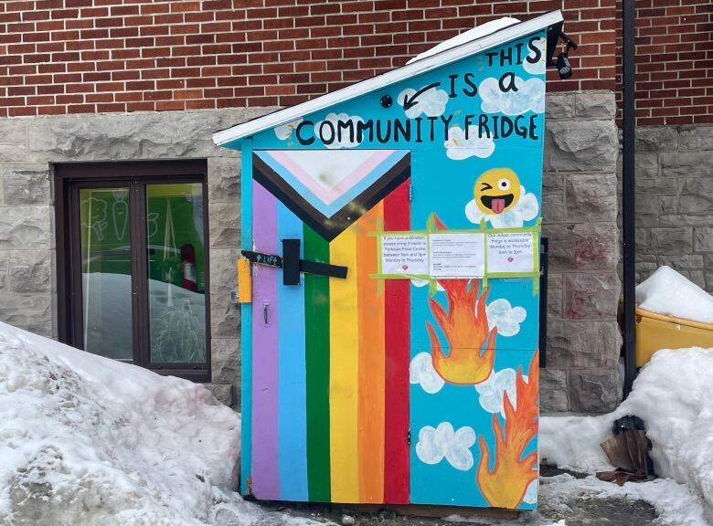 A decorated shed with a sign saying 'This is a community fridge.'